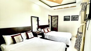 A hotel room with two beds, a large mirror, and a ceiling light fixture.