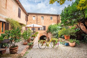 A courtyard with a bicycle, potted plants, and a brick building.