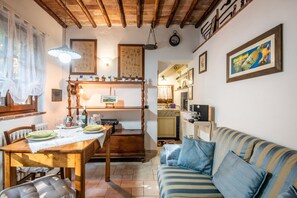 A cozy living room with a wooden dining table, a striped sofa, and a kitchen area in the background.
