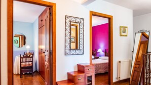 Una habitación con un armario de madera, un espejo, una mesita de noche y una cama.