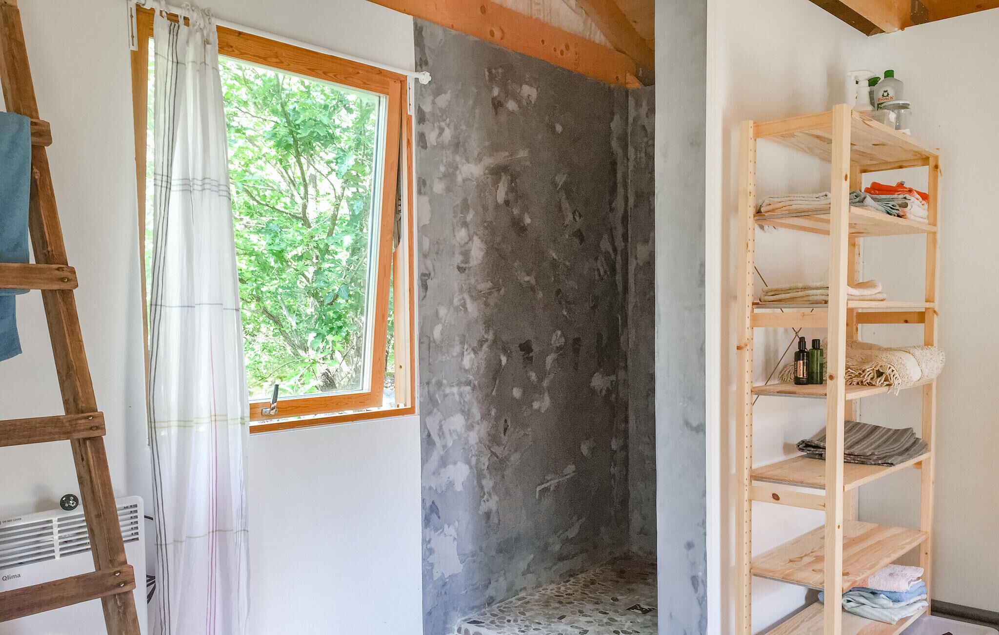 A room with a window, a wooden ladder, and a metal shelf unit.