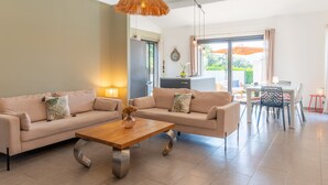 A modern living room with a sofa, coffee table, and dining area. - Holiday Home 'Villabergerie En Pierre Du Pays' with Private Pool, Wi-Fi and Air Conditioning (Barbaggio)