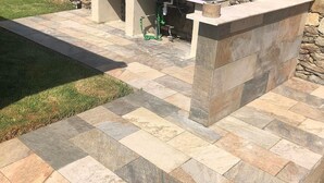A patio area with stone tiles, a grassy lawn, and a stone wall.