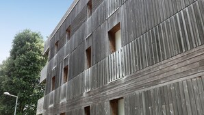 Un immeuble à plusieurs étages doté d’une façade en bois et de nombreuses fenêtres.