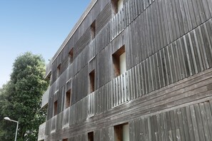 Ein mehrstöckiges Gebäude mit Holzfassade und zahlreichen Fenstern.