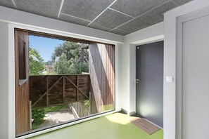 Ein Zimmer mit einem großen Fenster, einer Tür und einem grünen Boden.
