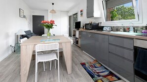Une cuisine moderne avec un coin repas, une grande fenêtre et une vue sur la verdure environnante.