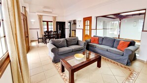 A living room with two grey sofas, a wooden coffee table, and a dining area with a table and chairs.