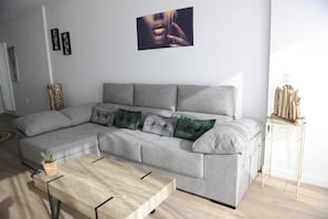A modern living room with a grey sectional sofa, a wooden coffee table, and a small side table with decorative items.