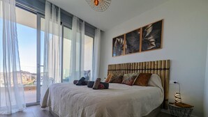 Ein Schlafzimmer mit einem großen Bett, Blick durch ein Fenster und einem Gemälde an der Wand.