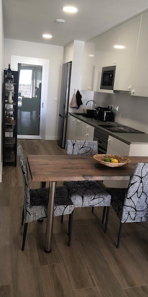 A modern kitchen with a dining table and chairs, a refrigerator, a microwave, and a sink.