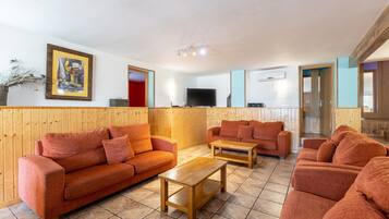 A room with wooden paneling, two sofas, a coffee table, a flat-screen TV, and a painting on the wall.