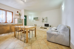 A modern kitchen with a dining table and chairs, a sofa, a TV, and a small plant. - Apartment 'Casa Martina' with Mountain View, Private Terrace and Wi-Fi (Sassetta)