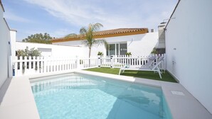 A swimming pool with a white fence, a white building, and a palm tree. - Holiday Home 'Casa Turquesa' with Private Pool, Wi-Fi and Air Conditioning (Conil de la Frontera)