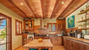 A kitchen with wooden cabinets, a dining table with chairs, and a coffee machine.