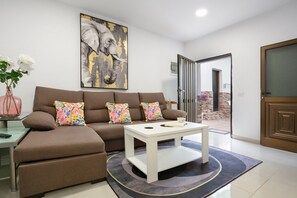 Una sala de estar con sofá, mesa de centro y una obra de arte en la pared.