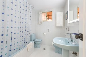 Ein Badezimmer mit Toilette, Waschbecken, Duschvorhang und einem Fenster mit Blick.