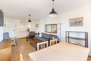 A living room with a sofa, chairs, a dining table, and a TV. - Apartment 'Zambra 3 - 311' with Shared Pool, Wi-Fi and Air Conditioning (La Manga del Mar Menor)