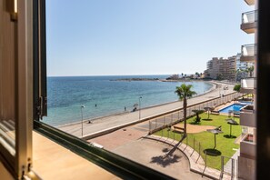 A view of a beach with a pool and a building in the background. - Apartment 'Zambra 3 - 311' with Shared Pool, Wi-Fi and Air Conditioning (La Manga del Mar Menor)