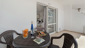 Un coin repas avec une table, des chaises, un verre d’eau, une bouteille et un bol de nourriture.