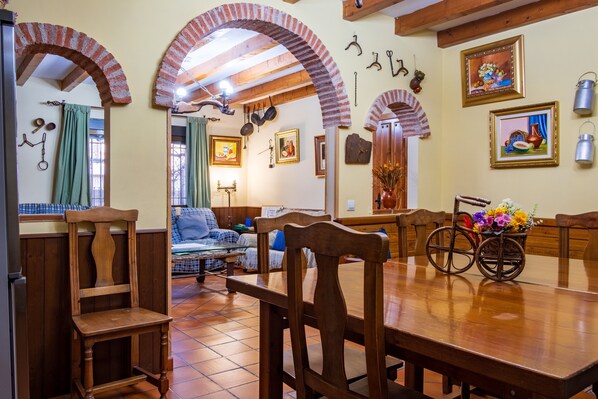 A dining area with wooden furniture, brick arches, and a dining table with chairs.