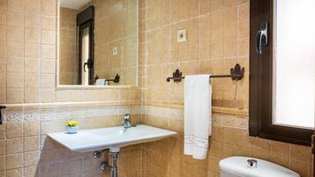 Un bagno con lavandino bianco, un water, uno specchio e un portasciugamani.