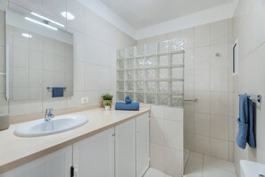 A bathroom with a sink, mirror, shower, and toilet.