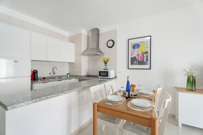 A modern kitchen with white cabinets, a granite countertop, a microwave, and a sink.