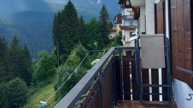 A balcony with a view of mountains, a wooden ceiling, and a tiled floor. - Casa Mazzagno Room with Wi-Fi (Comelico Superiore)