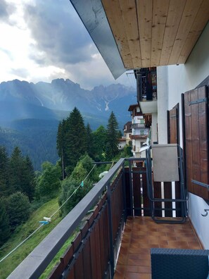 Un balcon avec vue sur les montagnes, un plafond en bois et un sol carrelé.