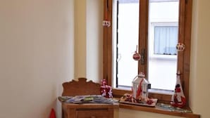 A corner room with a wooden cabinet, a small window with decorations, and a Santa Claus figure.