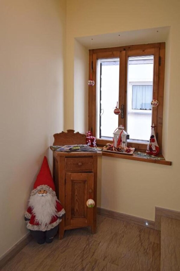 A corner room with a wooden cabinet, a small window with decorations, and a Santa Claus figure.