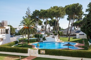 A swimming pool surrounded by neatly trimmed hedges and trees, with a clear sky above. - Apartment 'Vistahermosa' with Shared Pool, Wi-Fi and Air Conditioning (El Puerto de Santa María)