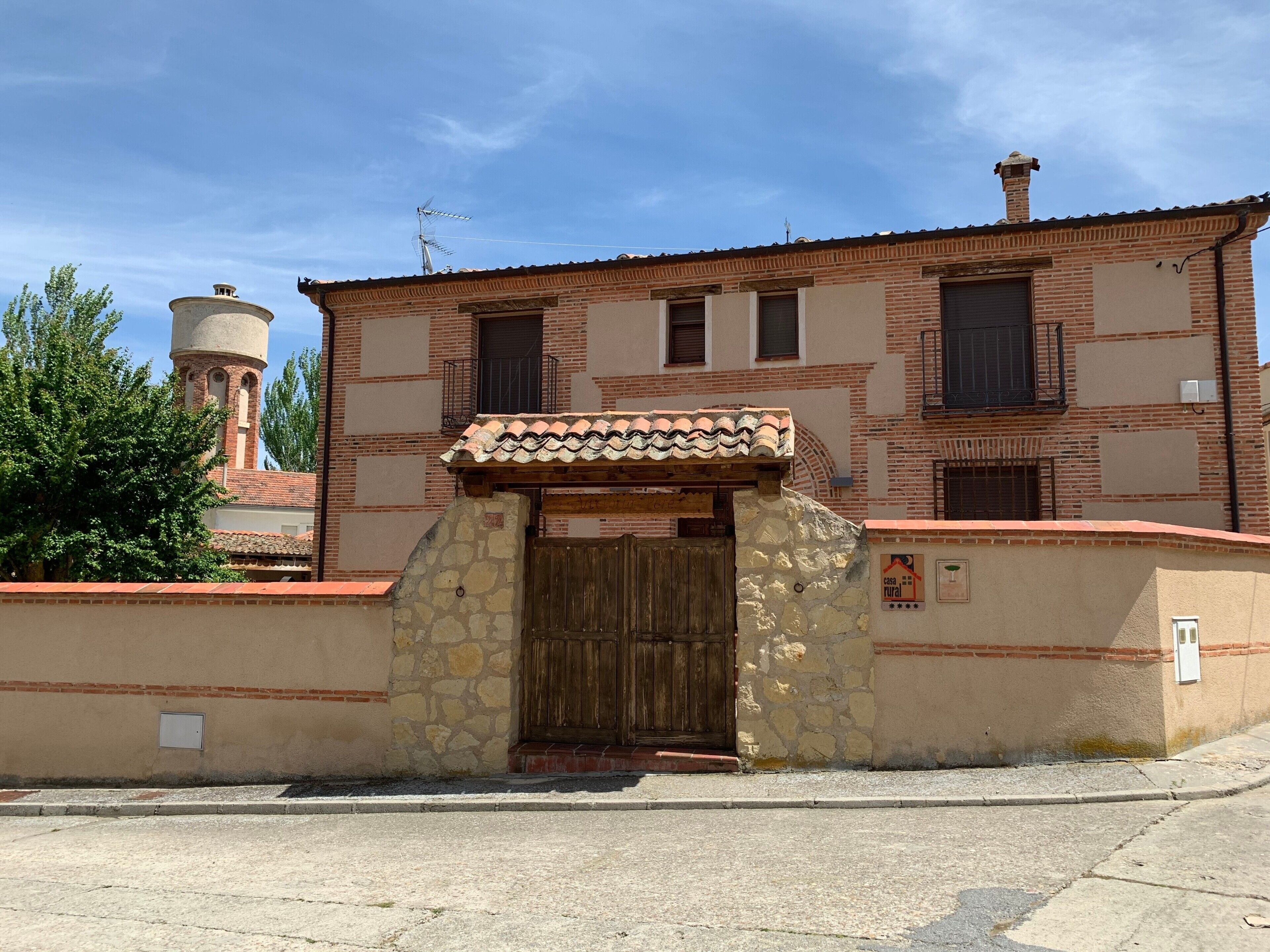 Un bâtiment à deux étages, doté d’un toit recouvert de tuiles, d’un portail d’entrée en pierre et d’un petit balcon.