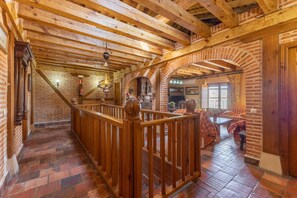 Un intérieur en bois avec un escalier, des murs en briques et une rambarde en bois.
