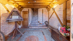Un interior de madera con una escalera, una mesa de madera con un libro y una cesta de flores.