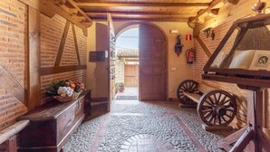 Un pasillo rústico con vigas de madera, suelo de baldosas de piedra y un banco de madera.