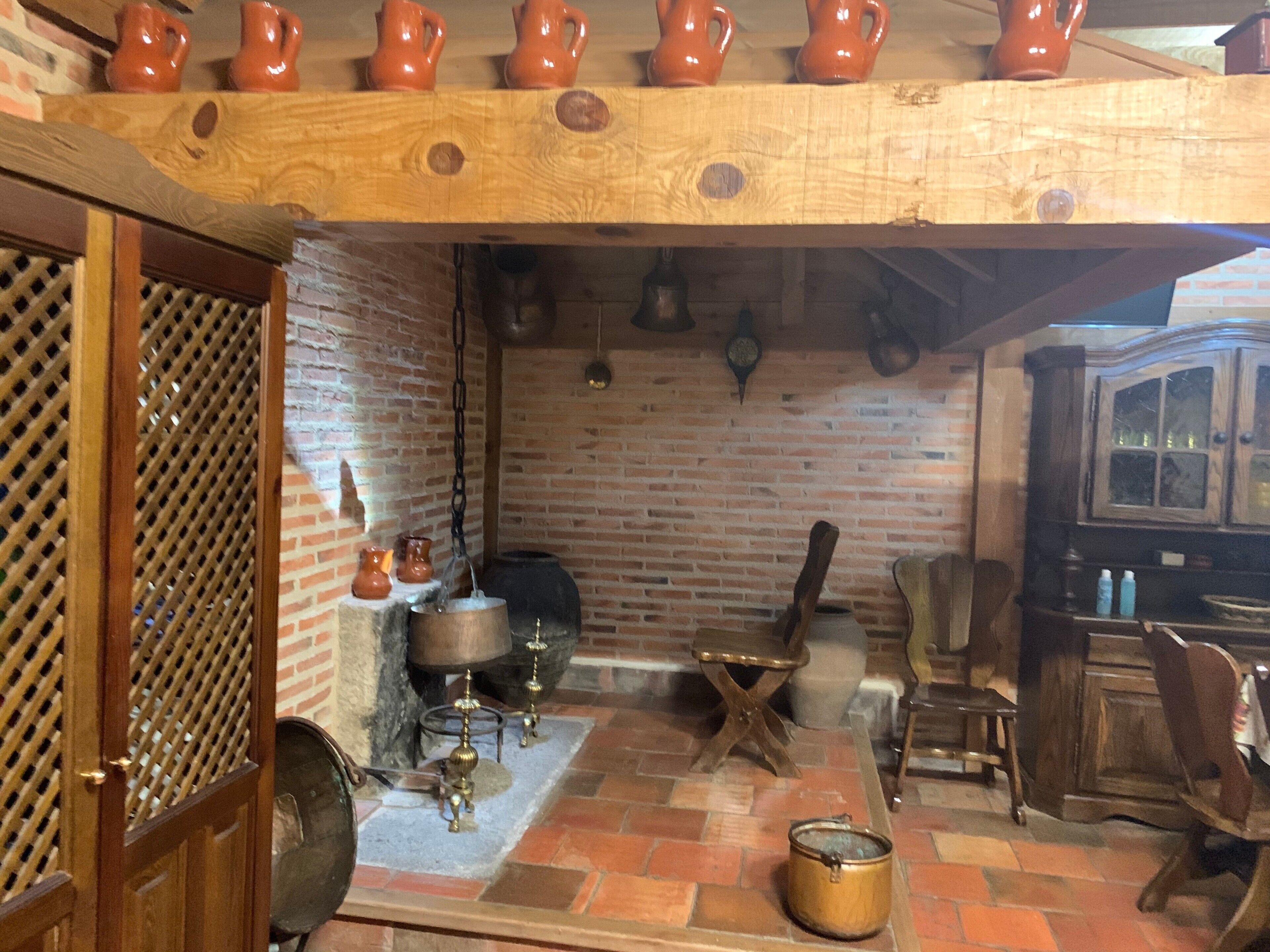 Une cuisine rustique avec un mur en briques, des poutres en bois et un porte-ustensiles suspendu.
