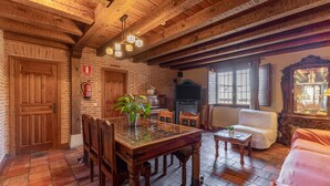 Un interior rústico con vigas de madera a la vista, una mesa de comedor con sillas, un sofá y una chimenea.