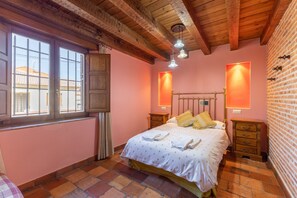 A bedroom with a bed, bedside tables, a window, and a brick wall.