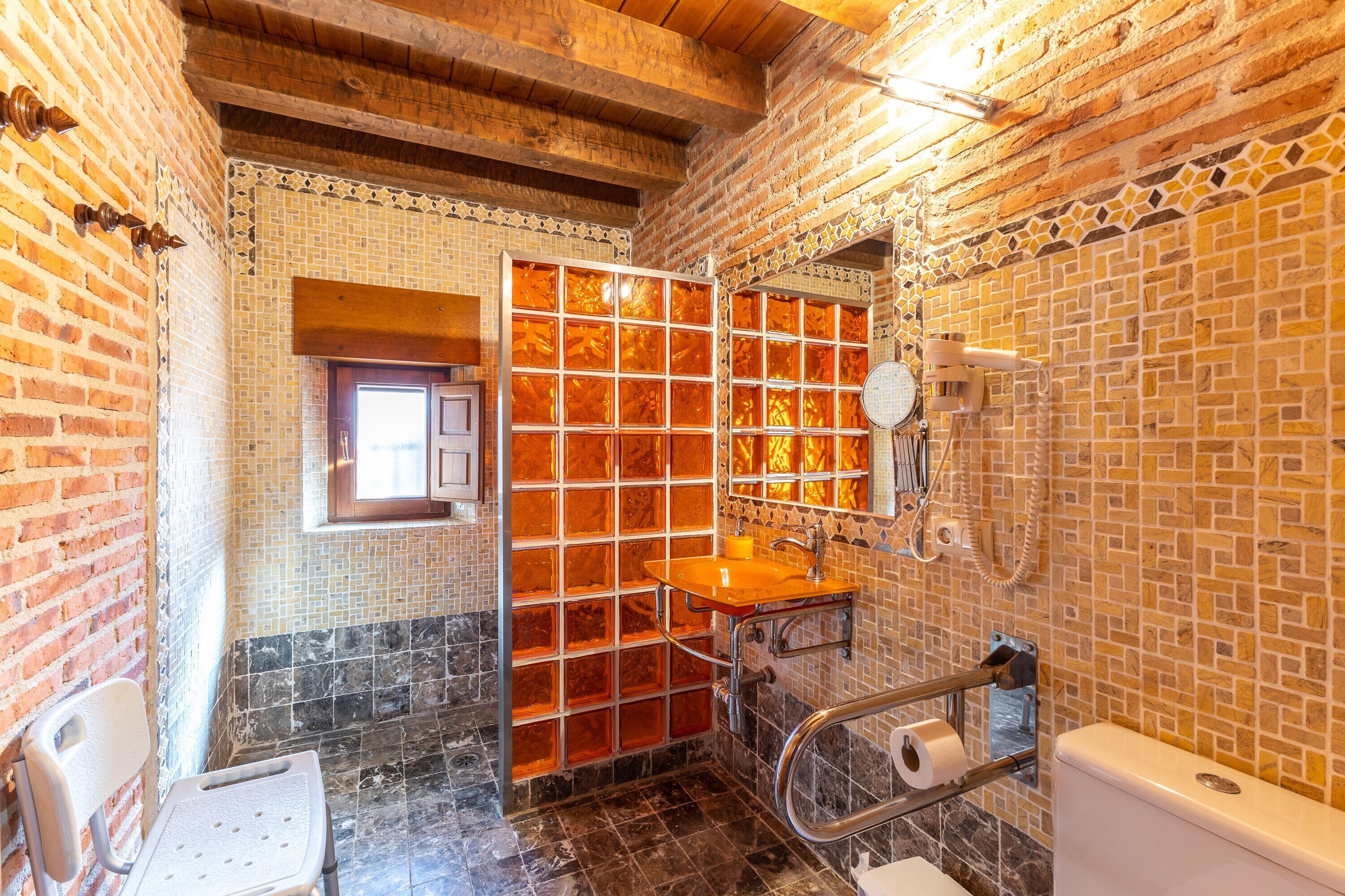 A bathroom with a tiled wall, a wooden bench, a sink, and a toilet.