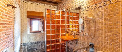 A bathroom with a tiled wall, a wooden bench, a sink, and a toilet.
