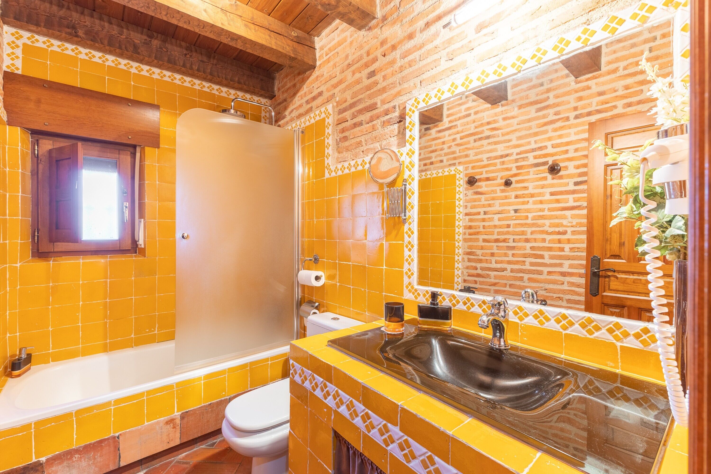 A bathroom with yellow tiles, a bathtub, a sink, and a mirror.