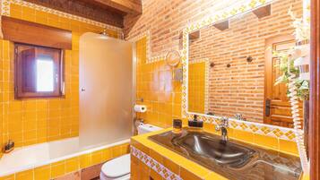 A bathroom with yellow tiles, a bathtub, a sink, and a mirror.