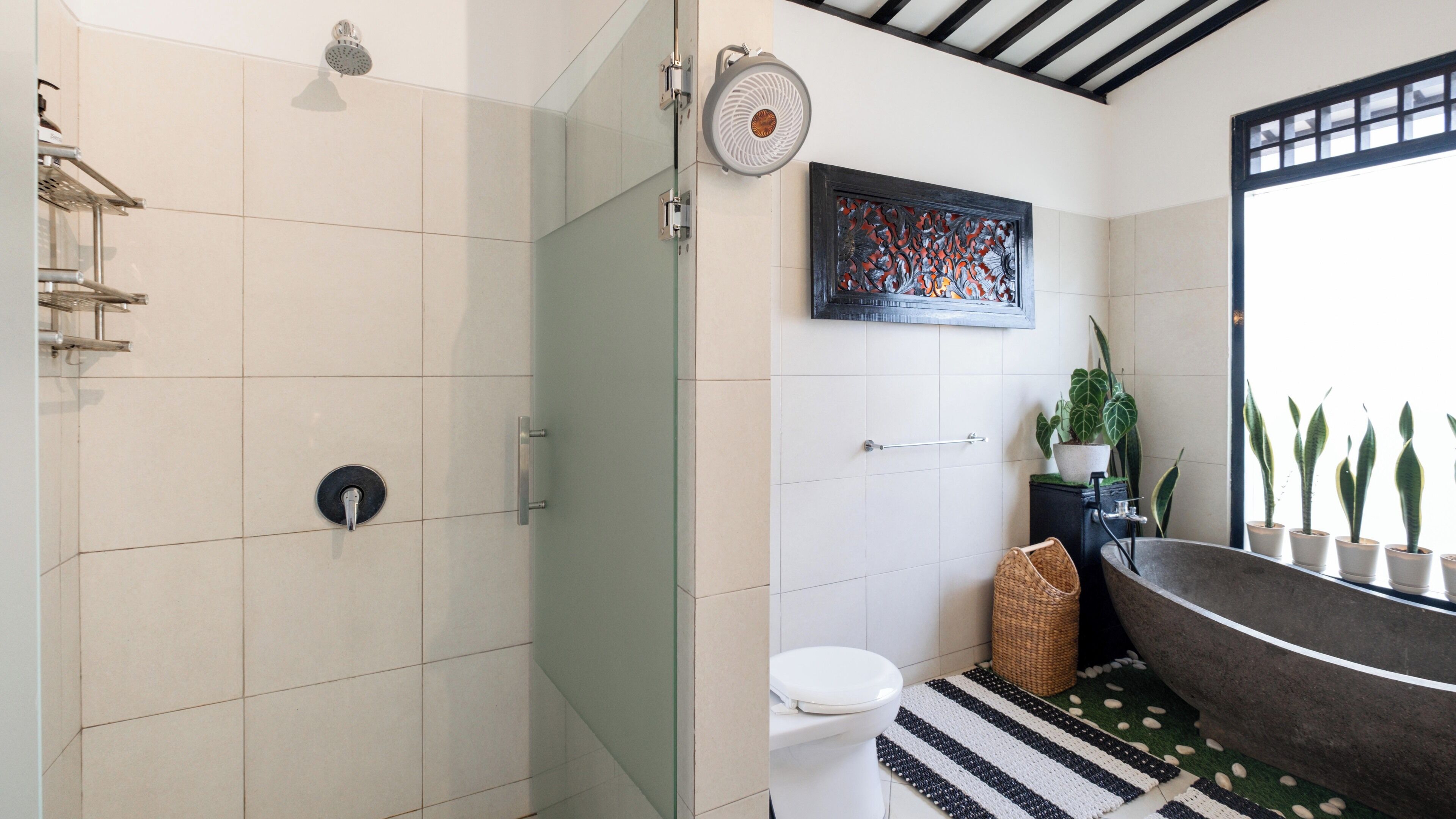 A modern bathroom with a glass shower enclosure, a freestanding bathtub, and a toilet.