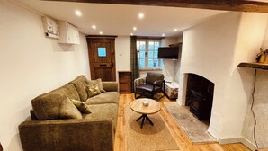 A cozy living room with a sofa, a small round table, a fireplace, and a television.