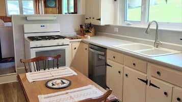 A kitchen with a stove, sink, and wooden dining table with chairs.