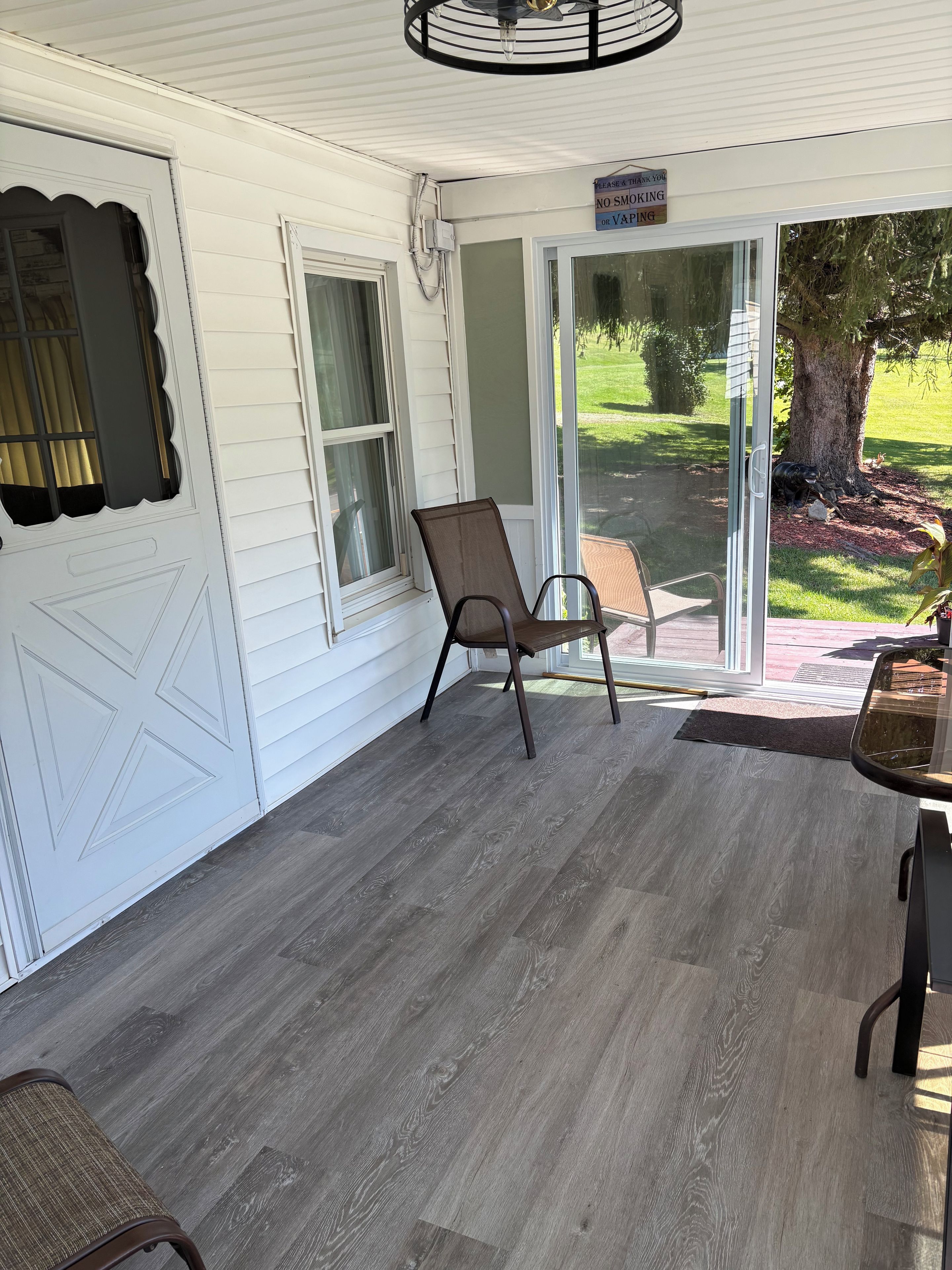 A covered porch with a chair, a table, and a door with a window.