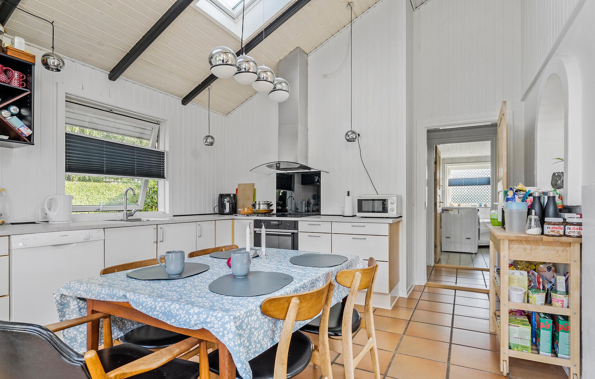 A spacious kitchen with a dining area, featuring a large island, modern appliances, and a view through the window.