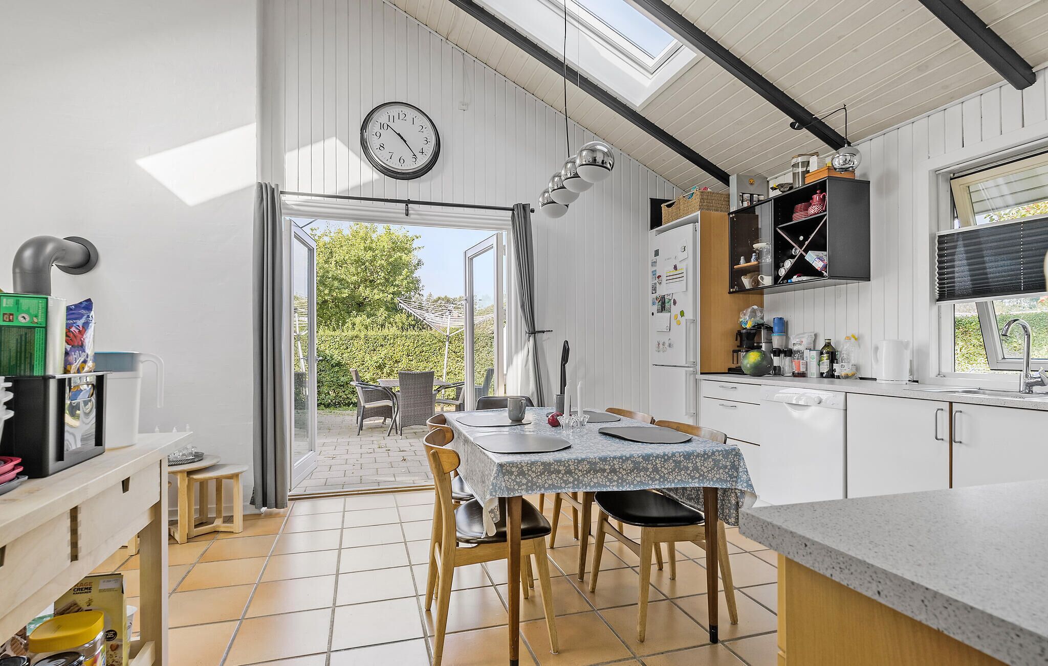 Et moderne køkken med spiseplads, med ovenlys, et ur og udsigt til haven.